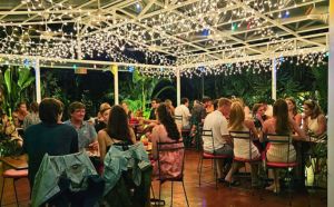 back patio at Café Milagro full of excited customers in the middle of the lush garden under twinkle lights